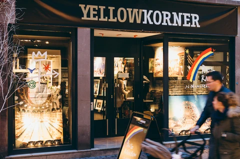 Devanture de magasin "YELLOWKORNER" avec vitrine éclairée présentant des photographies d'art encadrées