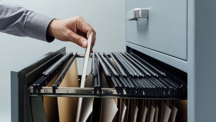 Employé à la recherche de fichiers dans un tiroir de l'armoire de classement en gros plan, concept d'administration et de stockage des données