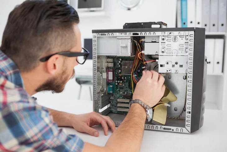 Le spécialiste technique du support à la clientèle parle sur un casque pendant qu'il travaille sur un ordinateur dans une salle de contrôle du centre d'appels, des écrans d'affichage remplis et des serveurs de données