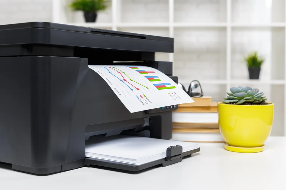 Bureau moderne avec imprimante multifonction noire en cours d'impression de graphiques colorés