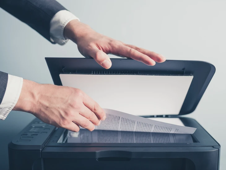 Personne en costume utilisant un scanner ou copieur multifonction dans un environnement de bureau
