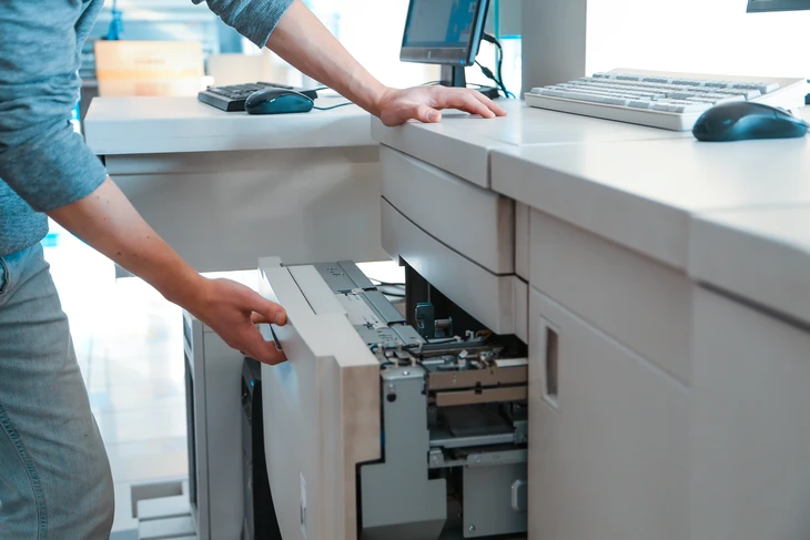 Scène de bureau moderne avec employé effectuant maintenance d'imprimante laser multifonction