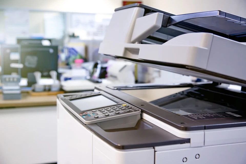 Bureau moderne avec imprimante multifonction professionnelle ouverte, révélant vitre de numérisation et bac d'alimentation papier