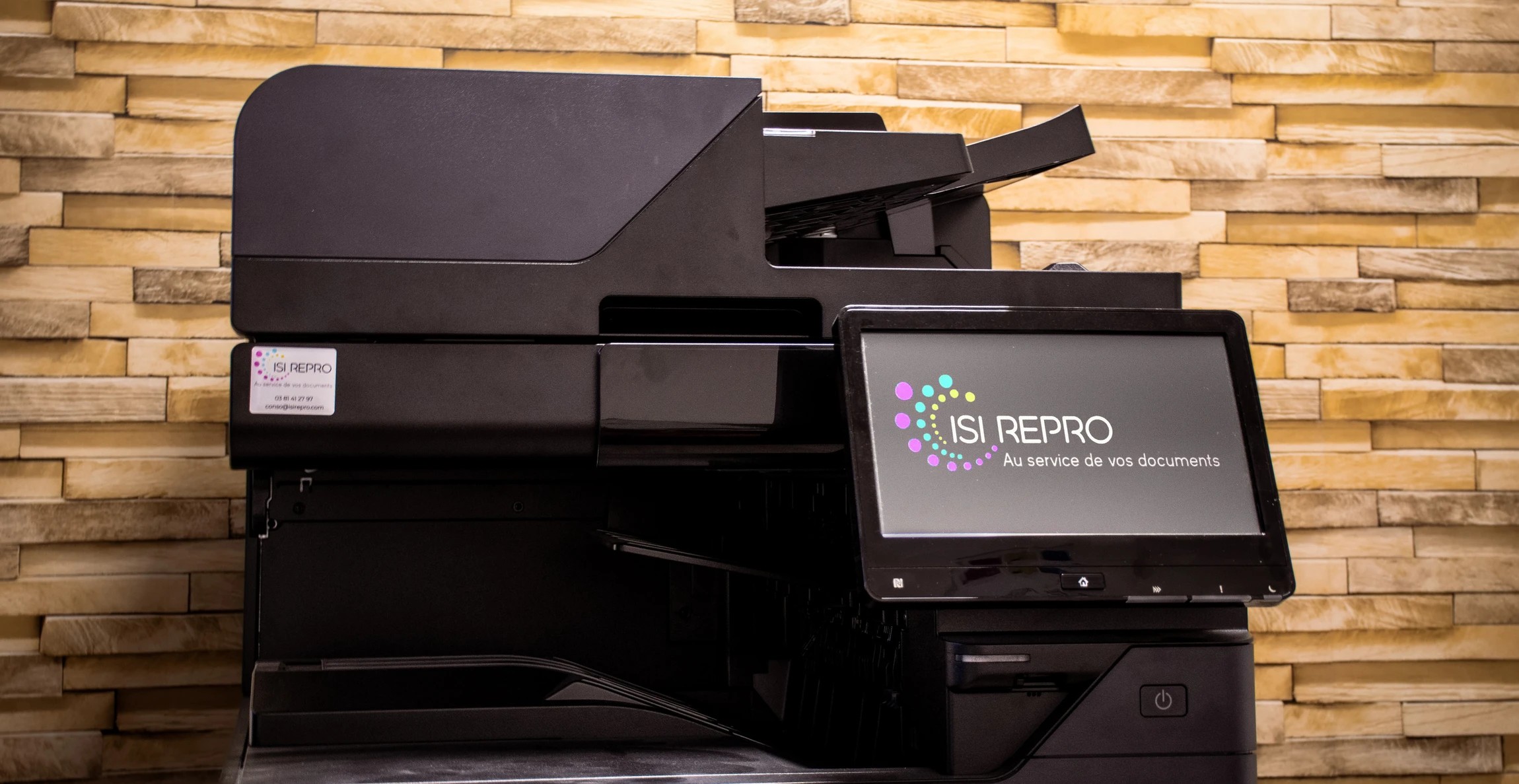 Bureau moderne avec imprimante multifonction professionnelle noire au premier plan, équipée d'écran LCD, clavier numérique et bac papier