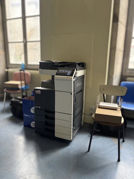 Scène de bureau moderne avec employé effectuant maintenance d'imprimante laser multifonction